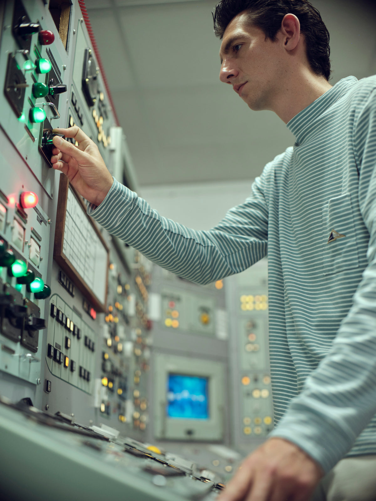Model wearing an Anglozine striped high-neck top beside an illuminated control panel.
